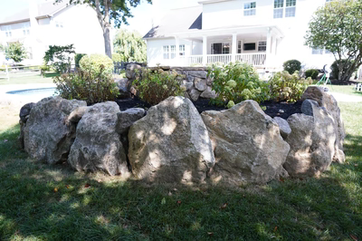 Multi-tiered natural stone boulder waterfall cascading into a pool surrounded by lush garden landscaping