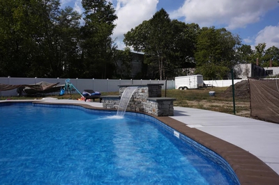 Multi-tiered natural stone boulder waterfall with sheet flow cascading into a curved swimming pool
