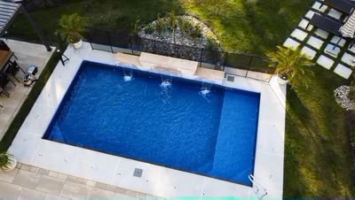 Single-tier natural stone boulder waterfall cascading into a blue pool with surrounding lush plants