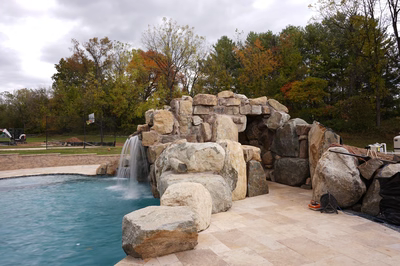 Single-tier natural stone boulder waterfall cascading into a pool surrounded by vibrant autumn trees