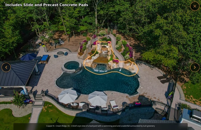 Multi-tiered natural stone boulder waterfall cascading into a freeform pool surrounded by lush greenery