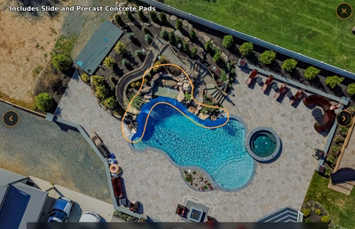 Multi-tiered natural stone boulder waterfall cascading into a freeform pool with lush green landscaping