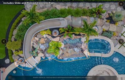 Multi-tiered natural stone boulder waterfall cascading into a pool surrounded by lush tropical plants