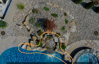 Multi-tiered natural stone boulder waterfall cascading into a pool surrounded by decorative garden plants