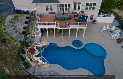 Two-tiered natural stone boulder waterfall cascading into a freeform pool with surrounding garden plants