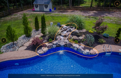 Triple-tiered natural stone boulder waterfall cascading into a blue pool surrounded by lush greenery