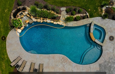 Multi-tiered natural stone boulder waterfall cascading into a freeform pool with lush garden landscaping