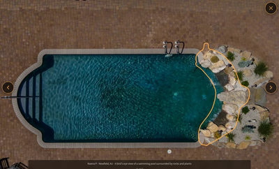 Multi-tiered natural stone boulder waterfalls cascading into a pool surrounded by ornamental garden plants
