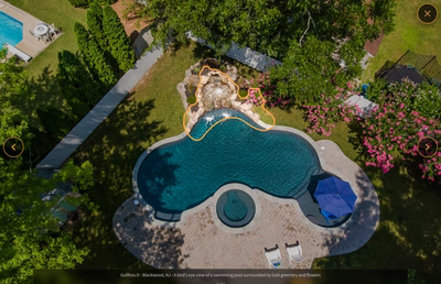 Multi-tiered natural stone boulder waterfall cascading into a freeform pool surrounded by lush greenery