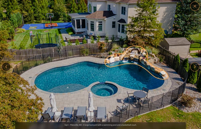 Multi-tiered natural stone boulder waterfall cascading into a freeform pool with surrounding garden plants