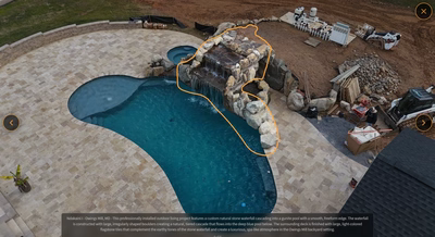 Two-tiered natural stone boulder waterfall cascading into a freeform pool with sparse tropical plants