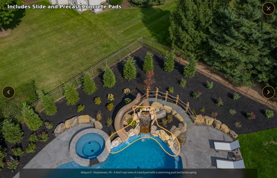 Two-tiered natural stone boulder waterfall cascading into a clear pool surrounded by lush evergreens