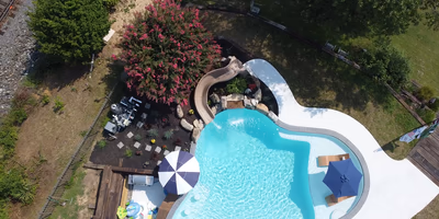 Single-tier natural stone boulder waterfall cascading into a freeform pool with lush garden landscaping