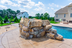 Patterson F - Medford, NJ - A large rock structure next to a swimming pool in a backyard.