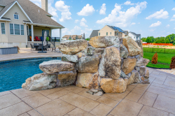 Patterson G - Medford, NJ - A large rock wall next to a swimming pool in a backyard.