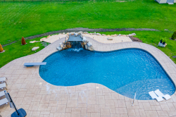 Patterson J - Medford, NJ - A swimming pool with a waterfall in the middle of a lush green yard